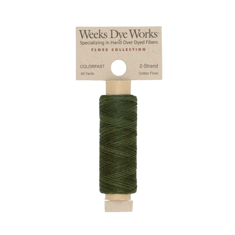 A spool of dark green embroidery floss with a tan label featuring the brand name and color information.