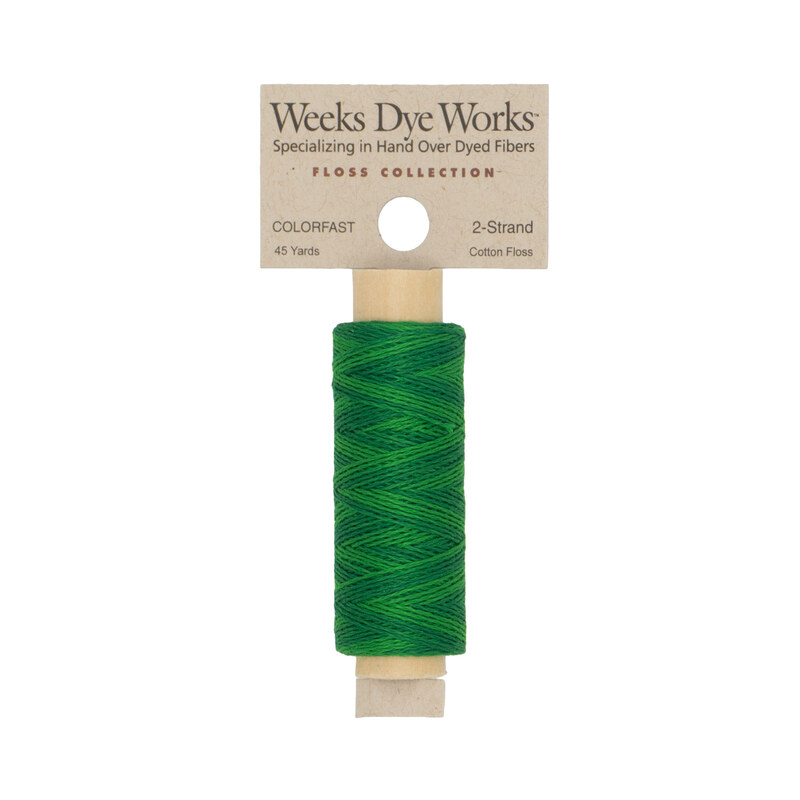 A spool of kelly green embroidery floss with a tan label featuring the brand name and color information.