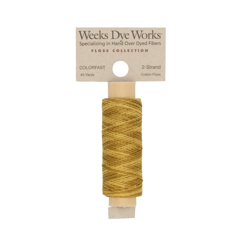 A spool of goldenrod embroidery floss with a tan label featuring the brand name and color information.