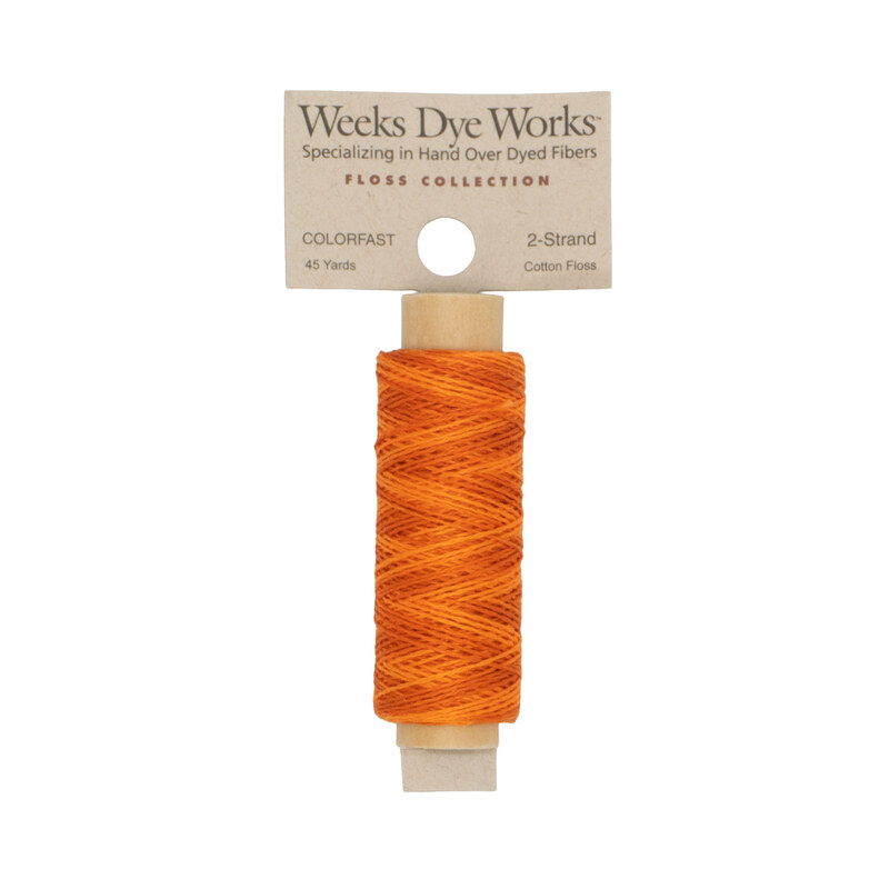 A spool of bright orange embroidery floss with a tan label featuring the brand name and color information.