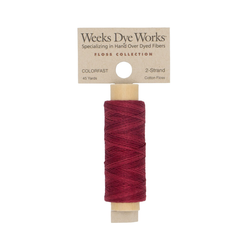 A spool of crimson embroidery floss with a tan label featuring the brand name and color information.