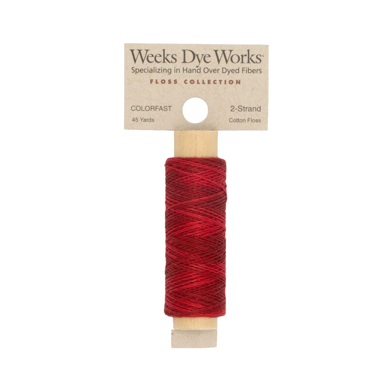 A spool of ruby red embroidery floss with a tan label featuring the brand name and color information.
