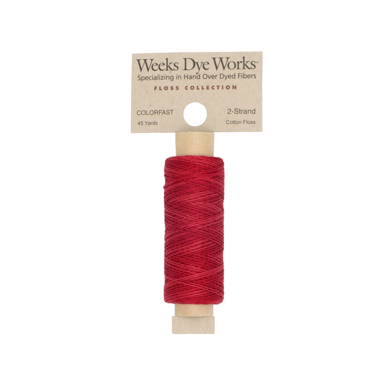 A spool of truck red embroidery floss with a tan label featuring the brand name and color information.