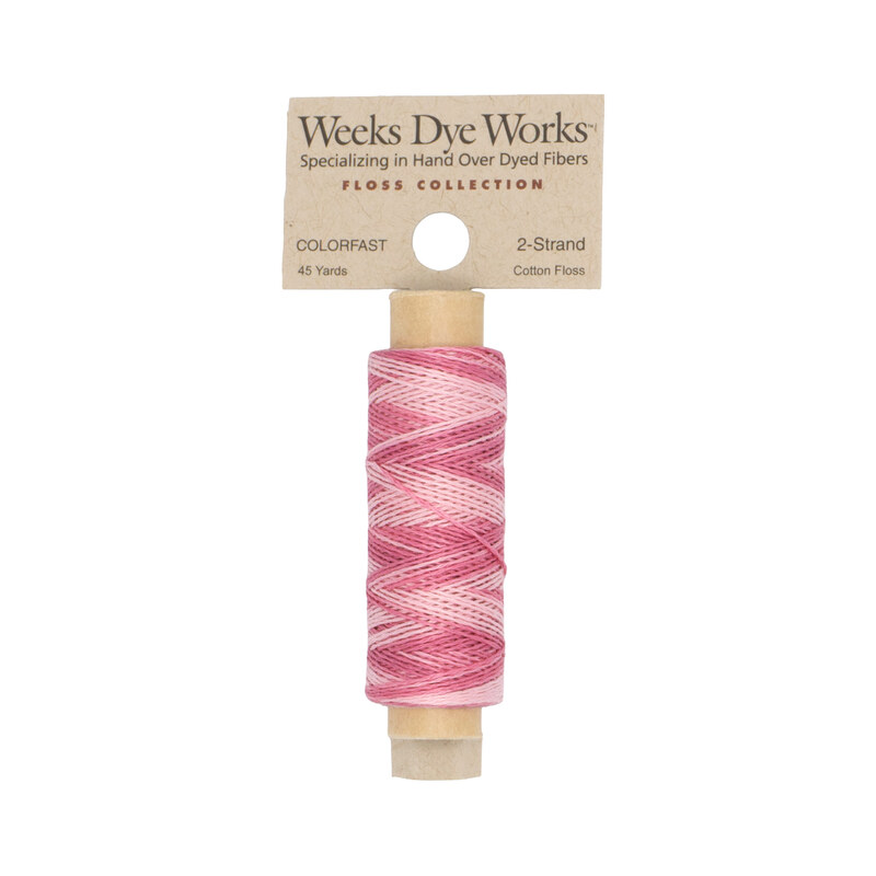 A spool of light and medium pink embroidery floss with a tan label featuring the brand name and color information.
