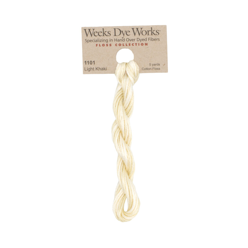 A skein of pale cream embroidery floss, twisted and bundled, with a tan label featuring the brand name and color information.