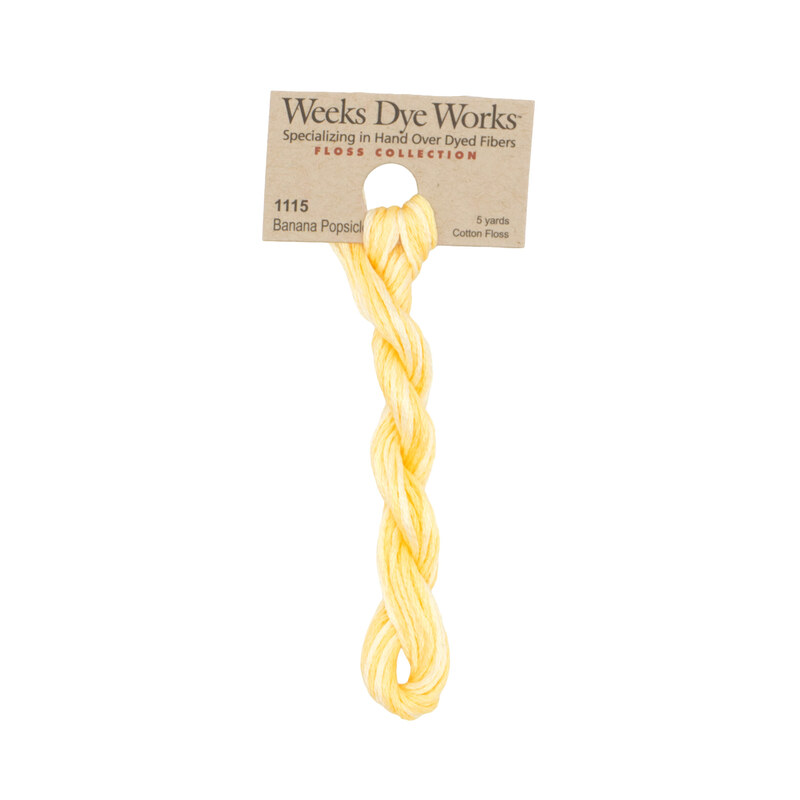 A skein of pale yellow embroidery floss, twisted and bundled, with a tan label featuring the brand name and color information.