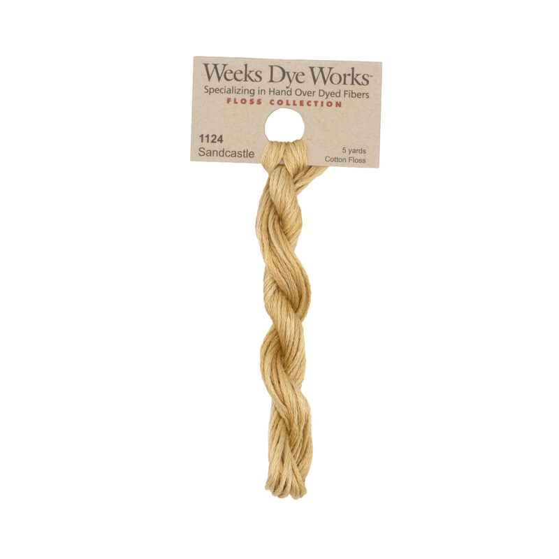 A skein of sand embroidery floss, twisted and bundled, with a tan label featuring the brand name and color information.
