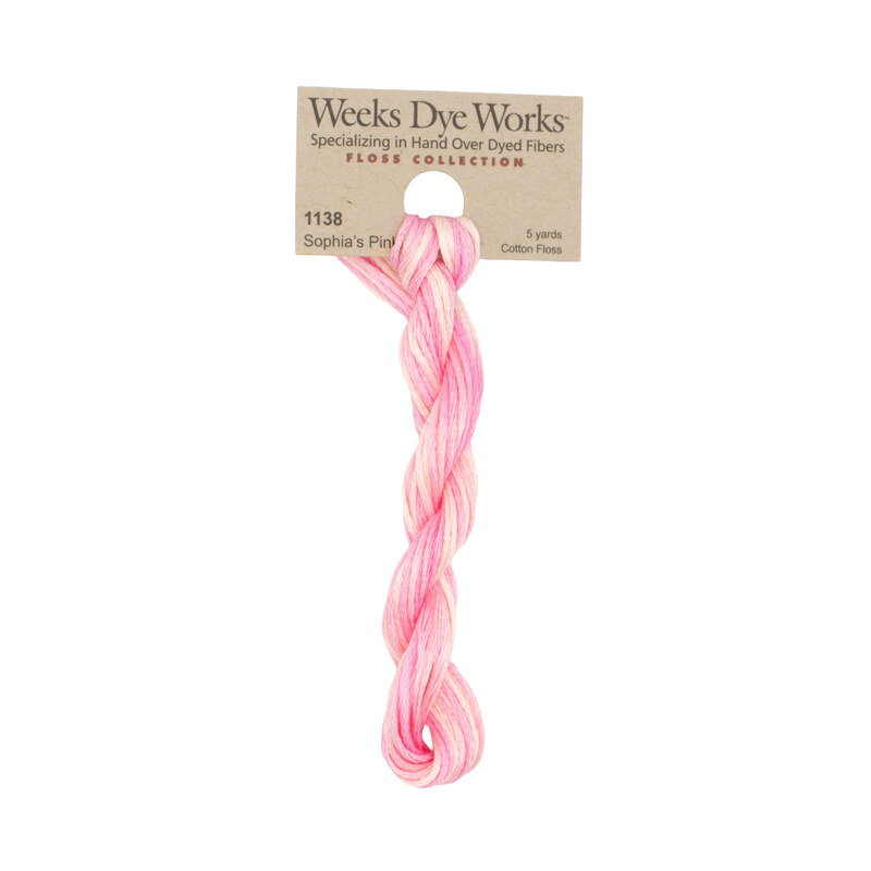 A skein of pink and cream embroidery floss, twisted and bundled, with a tan label featuring the brand name and color information.