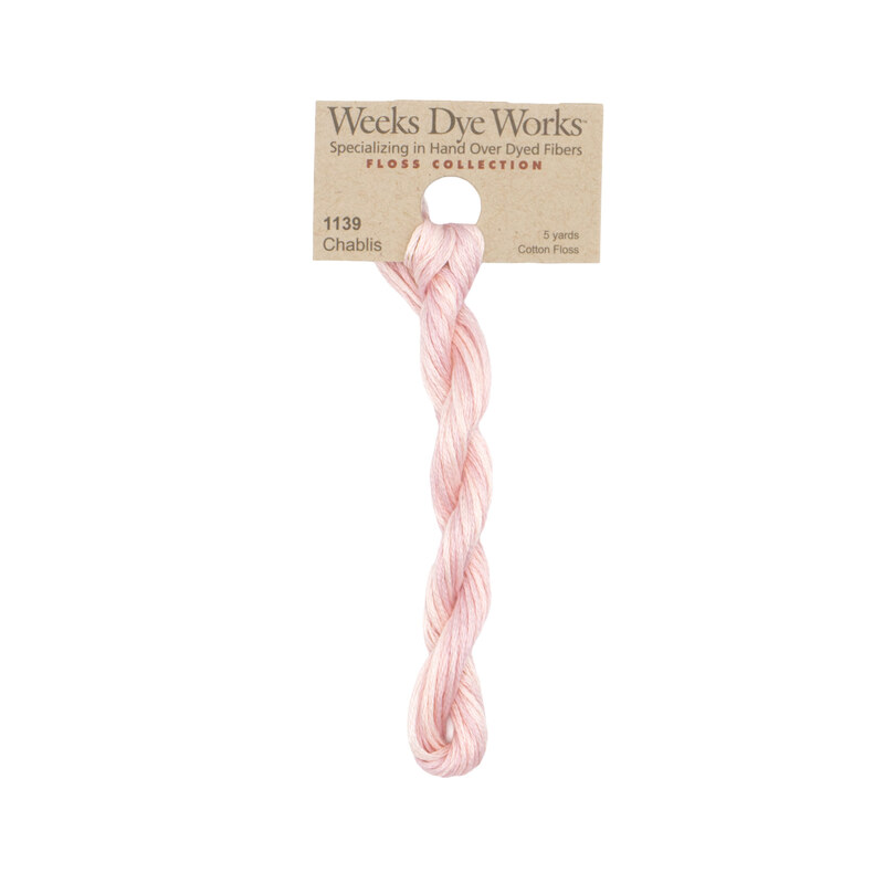 A skein of dusty rose pink embroidery floss, twisted and bundled, with a tan label featuring the brand name and color information.