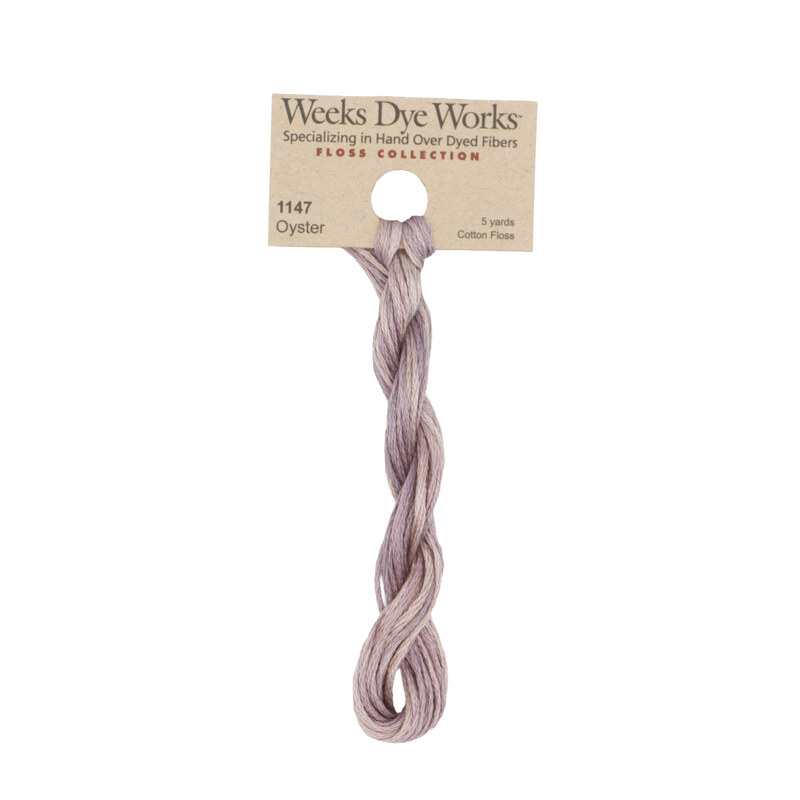 A skein of heather embroidery floss, twisted and bundled, with a tan label featuring the brand name and color information.