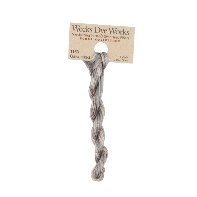 A skein of gray embroidery floss, twisted and bundled, with a tan label featuring the brand name and color information.