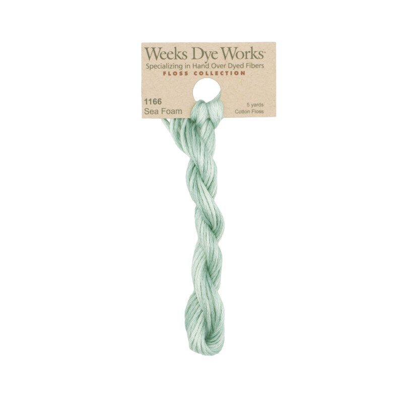 A skein of pale aqua embroidery floss, twisted and bundled, with a tan label featuring the brand name and color information.