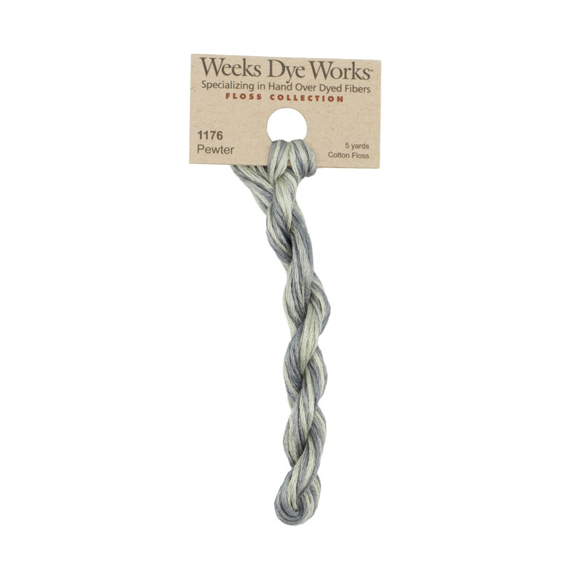 A skein of gray and blue embroidery floss, twisted and bundled, with a tan label featuring the brand name and color information.