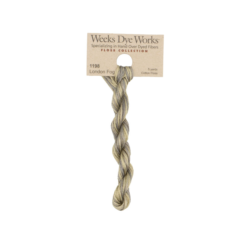 A skein of Variegated khaki and gray embroidery floss, twisted and bundled, with a tan label featuring the brand name and color information.