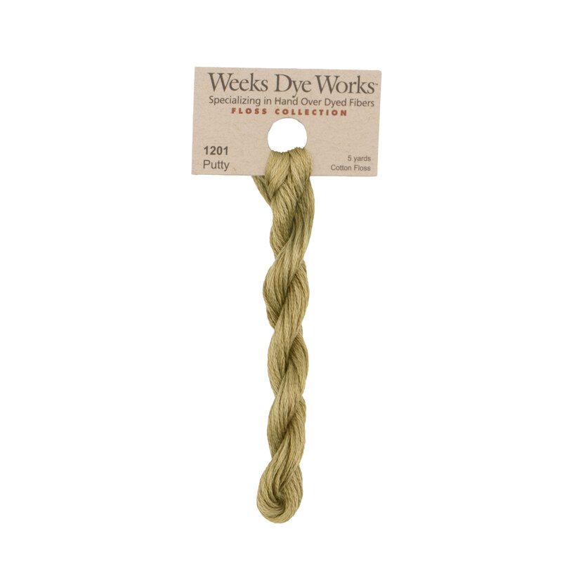 A skein of olive green embroidery floss, twisted and bundled, with a tan label featuring the brand name and color information.