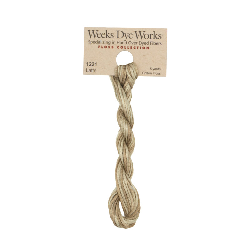 A skein of pale latte embroidery floss, twisted and bundled, with a tan label featuring the brand name and color information.