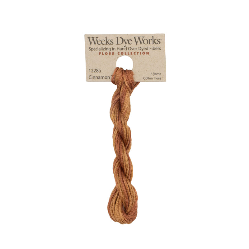 A skein of cinnamon embroidery floss, twisted and bundled, with a tan label featuring the brand name and color information.