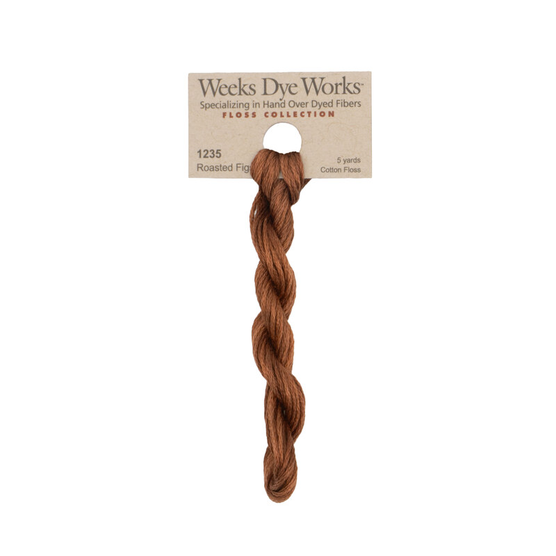 A skein of burnt sienna embroidery floss, twisted and bundled, with a tan label featuring the brand name and color information.