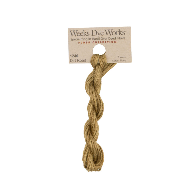 A skein of tan embroidery floss, twisted and bundled, with a tan label featuring the brand name and color information.