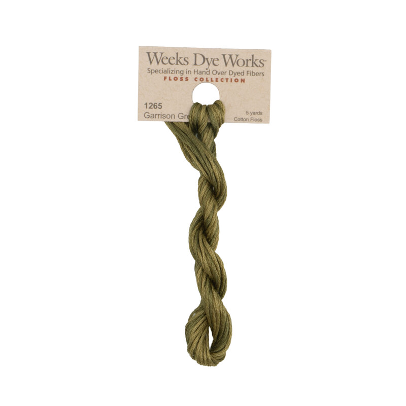 A skein of dark khaki embroidery floss, twisted and bundled, with a tan label featuring the brand name and color information.