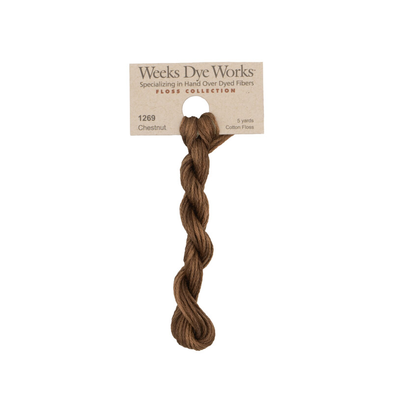 A skein of chestnut brown embroidery floss, twisted and bundled, with a tan label featuring the brand name and color information.