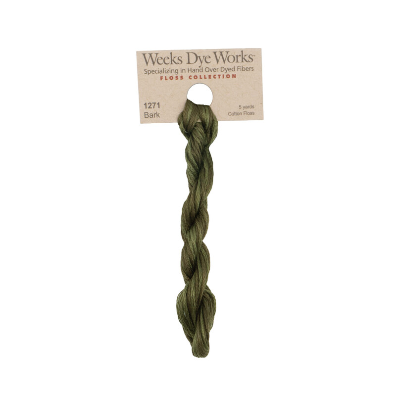 A skein of olive brown embroidery floss, twisted and bundled, with a tan label featuring the brand name and color information.