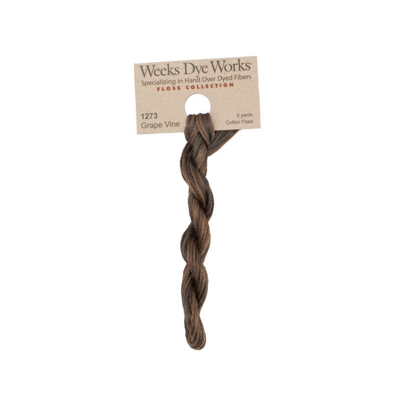 A skein of vine brown embroidery floss, twisted and bundled, with a tan label featuring the brand name and color information.