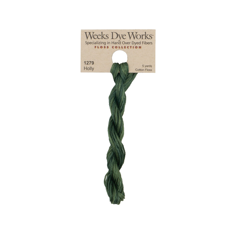 A skein of evergreen embroidery floss, twisted and bundled, with a tan label featuring the brand name and color information.