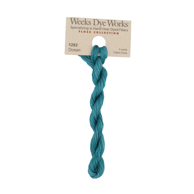 A skein of turquoise embroidery floss, twisted and bundled, with a tan label featuring the brand name and color information.?