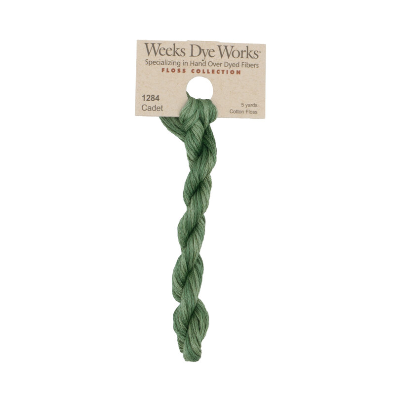 A skein of muted army green embroidery floss, twisted and bundled, with a tan label featuring the brand name and color information.