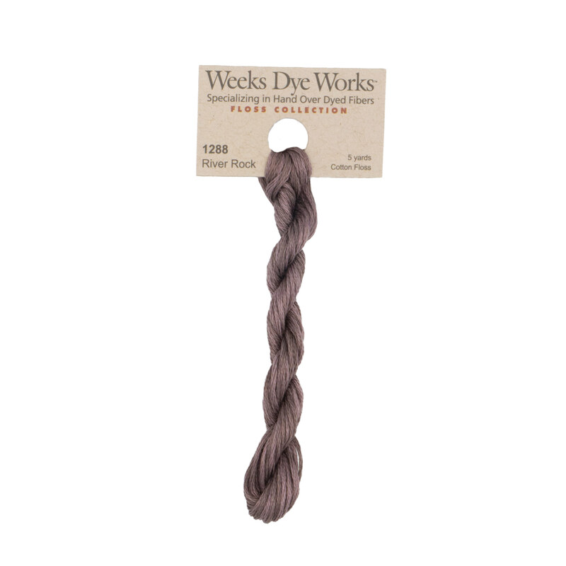 A skein of dusty mauve embroidery floss, twisted and bundled, with a tan label featuring the brand name and color information.