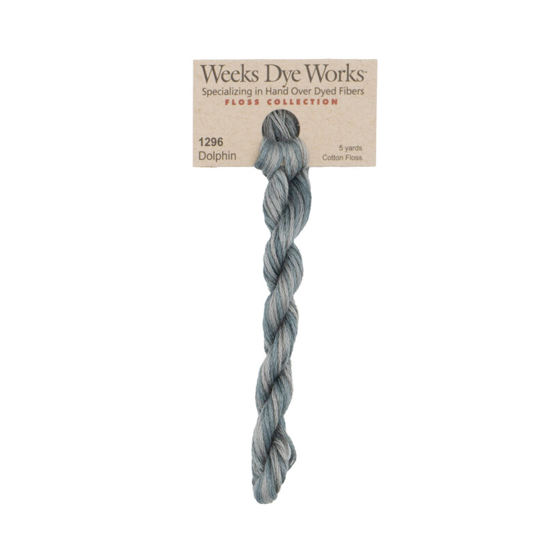 A skein of variegated gray embroidery floss, twisted and bundled, with a tan label featuring the brand name and color information.