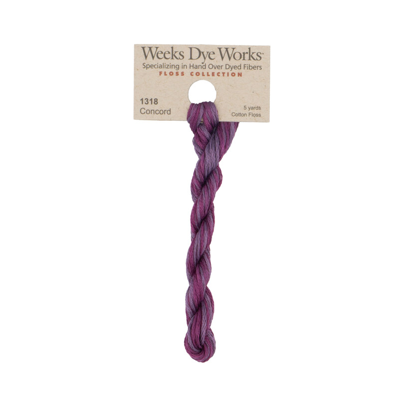 A skein tonal purple and magenta embroidery floss, twisted and bundled, with a tan label featuring the brand name and color information.