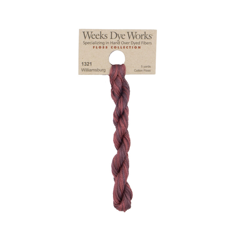 A skein of tonal pink-red embroidery floss, twisted and bundled, with a tan label featuring the brand name and color information.