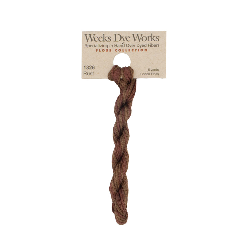 A skein of subtly variegated brown and auburn embroidery floss, twisted and bundled, with a tan label featuring the brand name and color information.