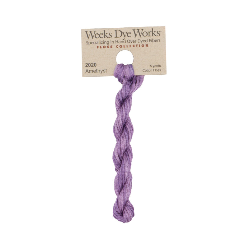 A skein of amethyst purple embroidery floss, twisted and bundled, with a tan label featuring the brand name and color information.