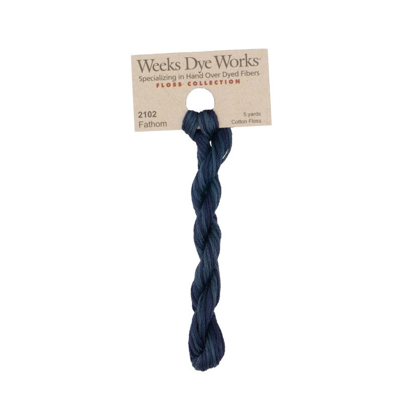 A skein of midnight blue embroidery floss, twisted and bundled, with a tan label featuring the brand name and color information.