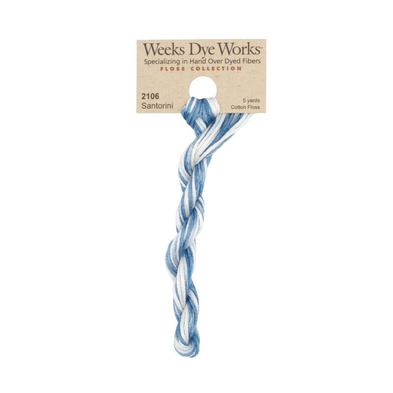 A skein of variegated blue and white embroidery floss, twisted and bundled, with a tan label featuring the brand name and color information.