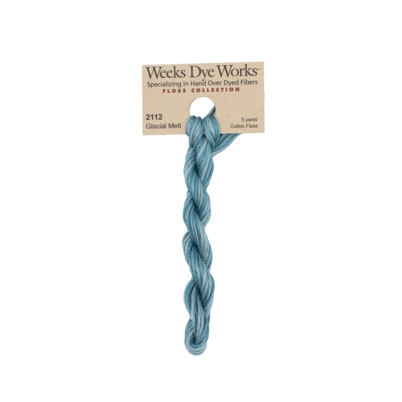 A skein of vintage blue embroidery floss, twisted and bundled, with a tan label featuring the brand name and color information.