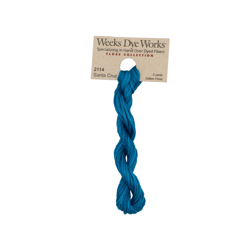 A skein of cerulean embroidery floss, twisted and bundled, with a tan label featuring the brand name and color information.