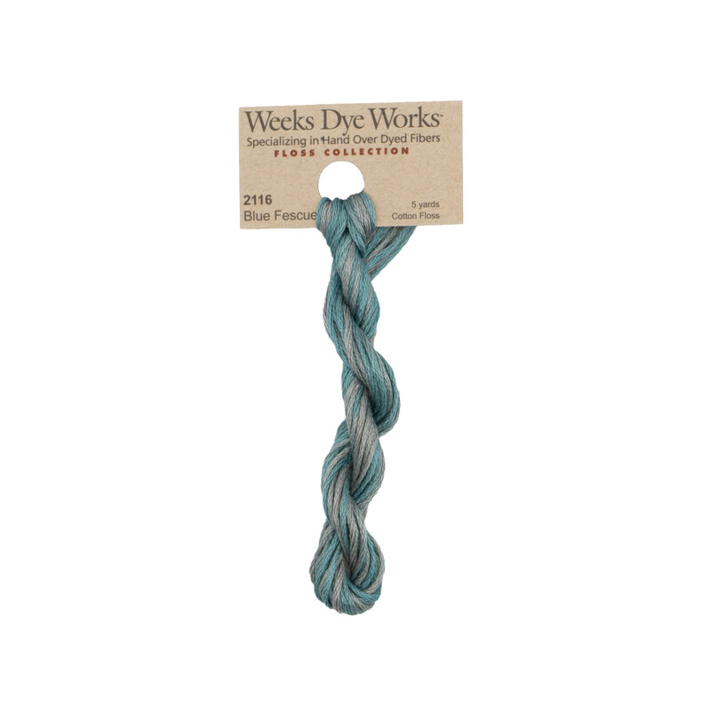 A skein of variegated medium teal and gray embroidery floss, twisted and bundled, with a tan label featuring the brand name and color information.
