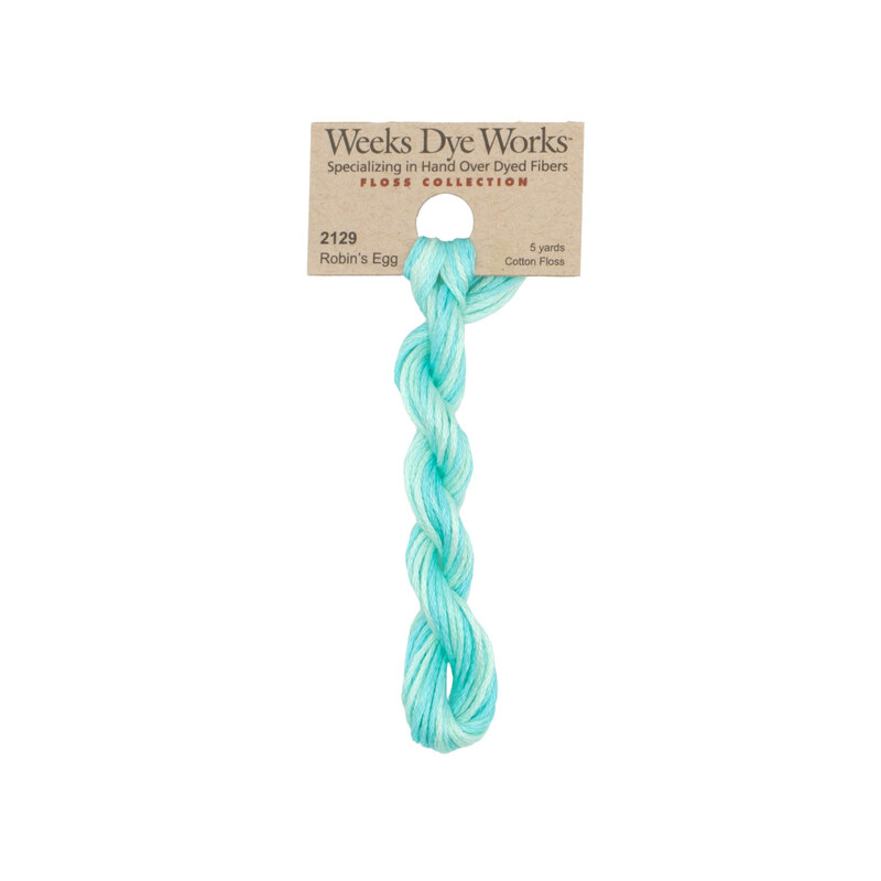 A skein of variegated aqua and robin's egg embroidery floss, twisted and bundled, with a tan label featuring the brand name and color information.