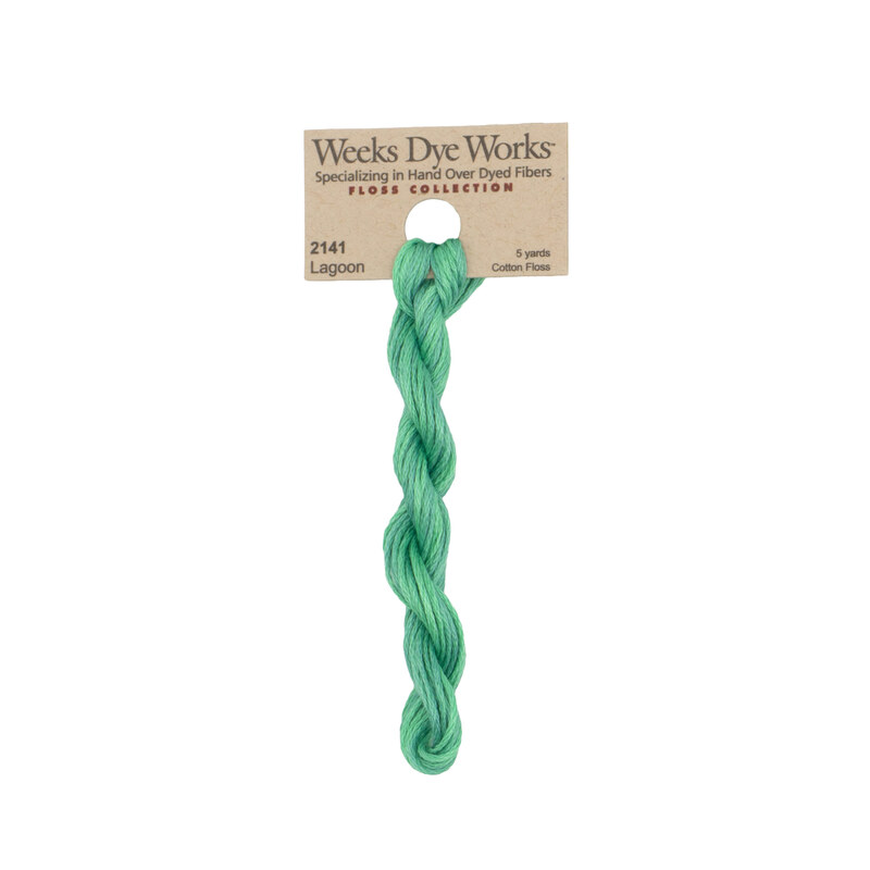 A skein of aqua green embroidery floss, twisted and bundled, with a tan label featuring the brand name and color information.