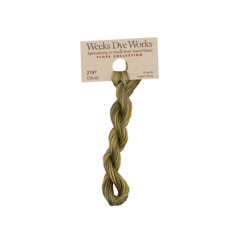 A skein of olive green embroidery floss, twisted and bundled, with a tan label featuring the brand name and color information.