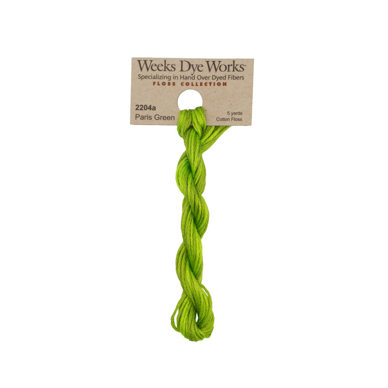 A skein of leaf green embroidery floss, twisted and bundled, with a tan label featuring the brand name and color information.
