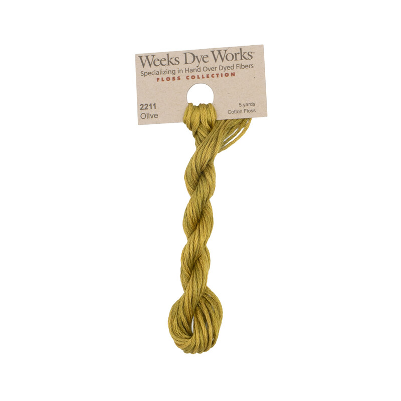 A skein of golden olive embroidery floss, twisted and bundled, with a tan label featuring the brand name and color information.