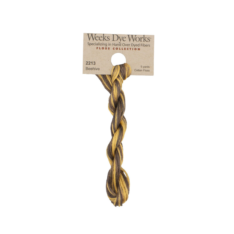 A skein of variegated dark walnut and butter embroidery floss, twisted and bundled, with a tan label featuring the brand name and color information.