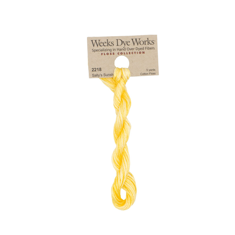A skein of pale yellow embroidery floss, twisted and bundled, with a tan label featuring the brand name and color information.