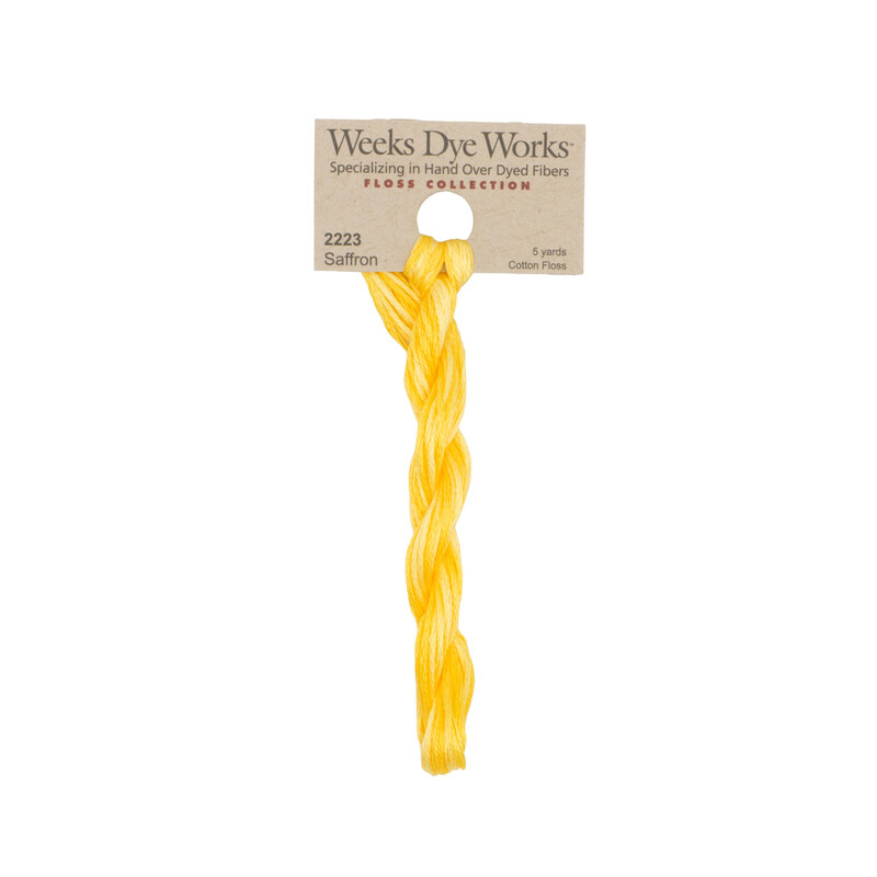 A skein of bright yellow embroidery floss, twisted and bundled, with a tan label featuring the brand name and color information.