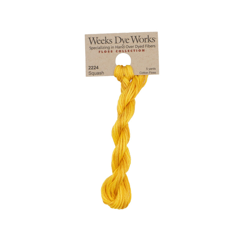 A skein of dandelion embroidery floss, twisted and bundled, with a tan label featuring the brand name and color information.